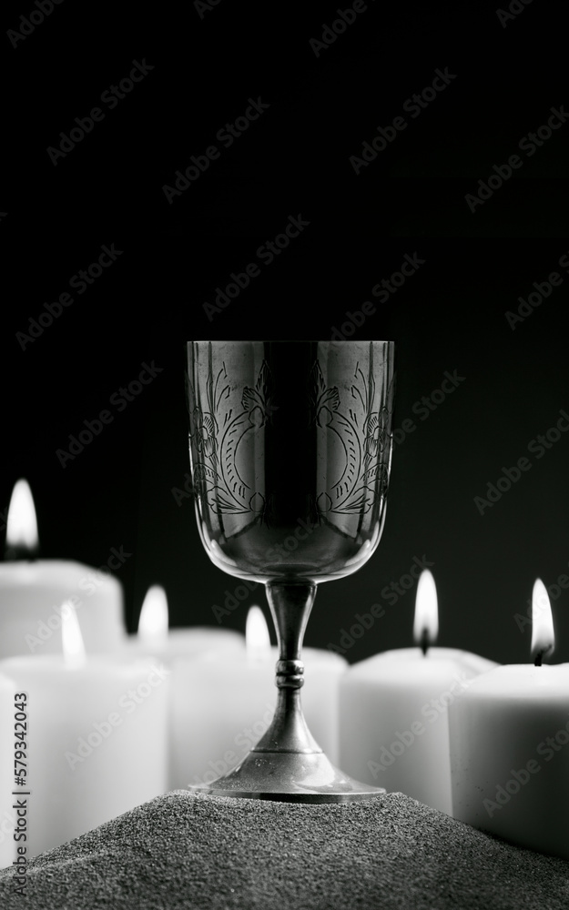 Fantastic metal chalice surrounded by candles on sand, text space, photograph in Black and White Fantastic metal chalice surrounded by candles on sand, text space, photograph in Black and White
