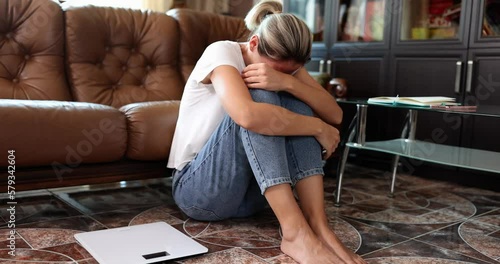 Woman suffering from depression and neurosis sits on floor and cries photo