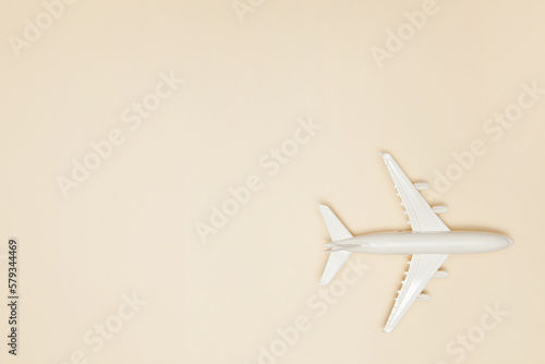 Airplane model. White plane on light brown background. Travel vacation concept. Summer background. Flat lay.