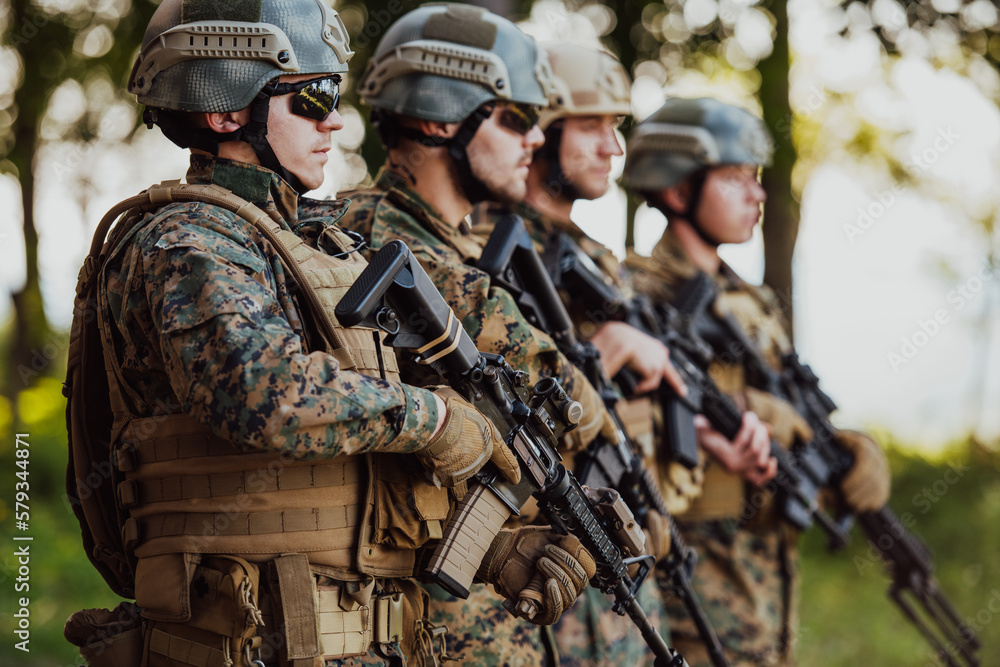 Fototapeta premium Soldier fighters standing together with guns. Group portrait of US army elite members, private military company servicemen, anti terrorist squad