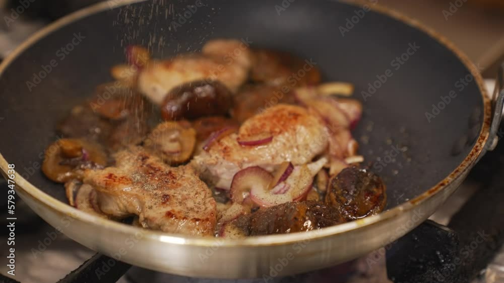 Chef adds seasonings to the pork tenderloins with onions and mushrooms in a pan. High quality 4k footage Chef adds seasonings to the pork tenderloins with onions and mushrooms in a pan. High quality 4k footage