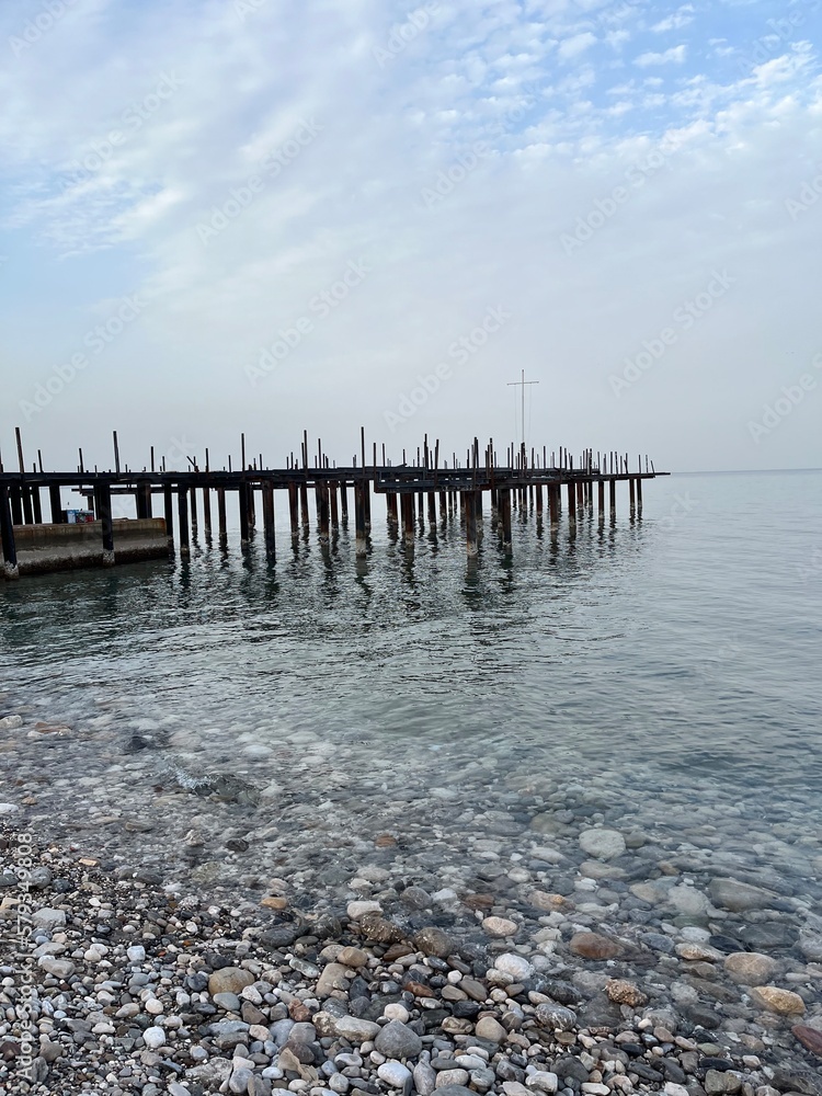 view of the sea pier on the beach with stones on a cloudy day