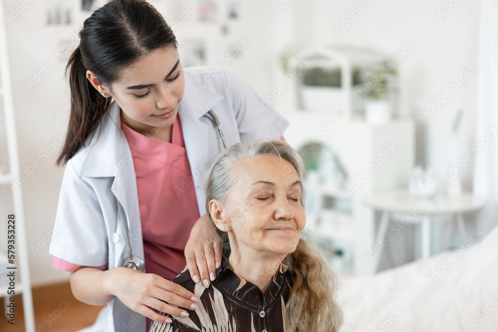 Obraz premium Doctor woman take care smiling older caucasian woman of shoulder massage home