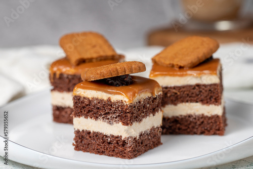 Small dessert cakes. Caramel petit four on a white plates in dark background. Biscuit french petit four cake. Close up