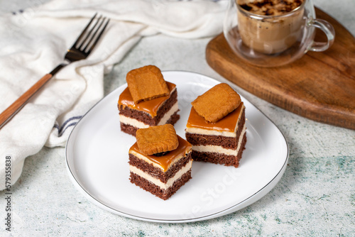 Small dessert cakes. Caramel petit four on a white plates in dark background. Biscuit french petit four cake