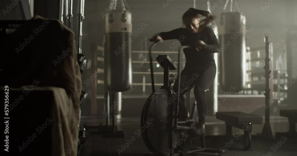 Sporty woman training on air bike in gymnasium Sporty woman training on air bike in gymnasium