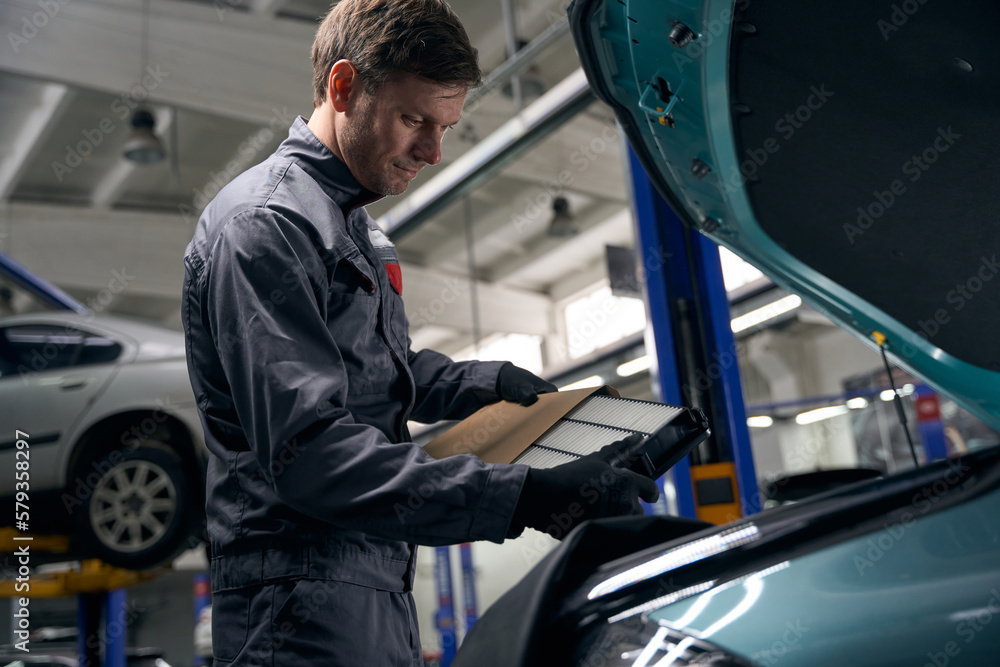Man holding parts for car repair in workshop Man holding parts for car repair in workshop