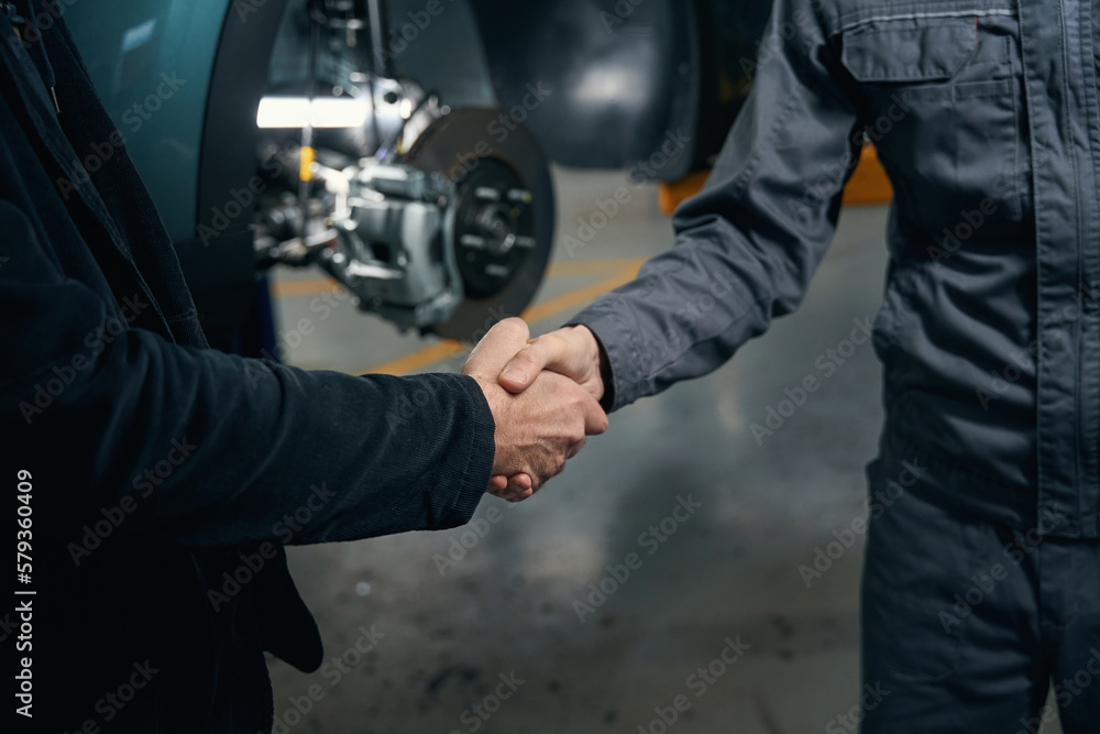 Mechanic talking with client and shaking hands - obrazy, fototapety, plakaty 