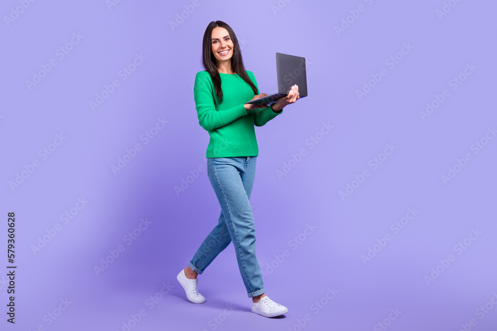 Full size profile photo of model woman walking advertising new netbook laptop limited collection isolated purple color background Full size profile photo of model woman walking advertising new netbook laptop limited collection isolated purple color background