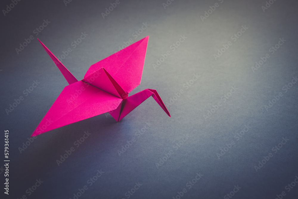 Pink paper crane origami isolated on a grey background Pink paper crane origami isolated on a grey background