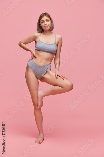 Beautiful slender young woman wearing grey cotton inner wear posing over pink background. Concept of natural beauty, body and skin care, healthy eating