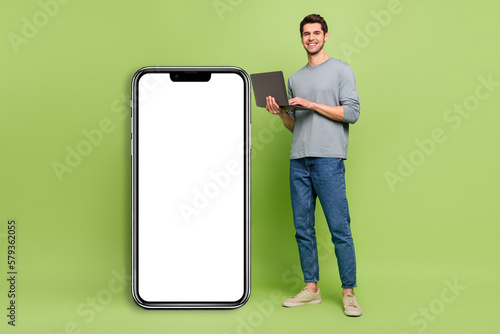 Full body photo of brown haired businessman promote smartphone placard isolated on green color background © deagreez