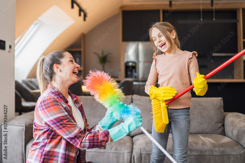 Happy mother and daughter having fun while cleaning house together. Happy mother and daughter having fun while cleaning house together.