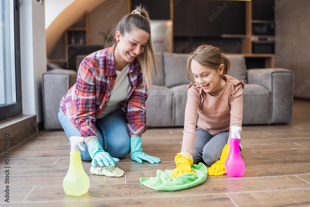 Fototapeta premium Happy mother and daughter cleaning house together.