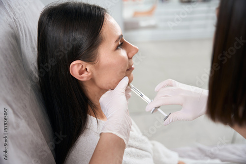 Lady on injection procedure for facial skin nutrition