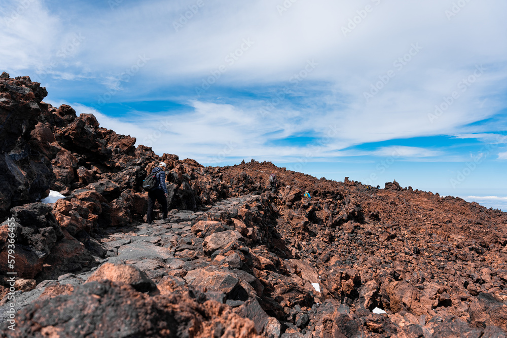 Obraz premium Turistas haciendo senderismo en montaña rocosa con vistas increíbles del horizonte con cielo azul y algunas nubes a más de 2000 metro, vistas desde el teide