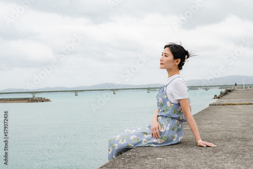 沖縄の堤防に座る女性 © NAMBA