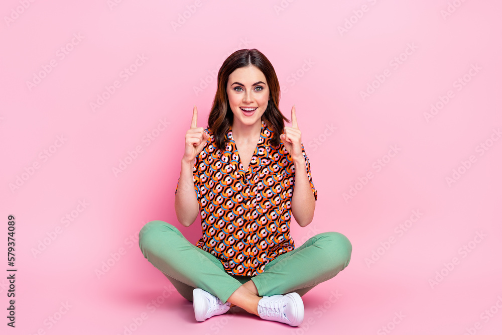 Full body photo of hipster funny girl sit crossed legs indicate fingers up useful tips how get crazy shopping sale isolated on pink color background Full body photo of hipster funny girl sit crossed legs indicate fingers up useful tips how get crazy shopping sale isolated on pink color background