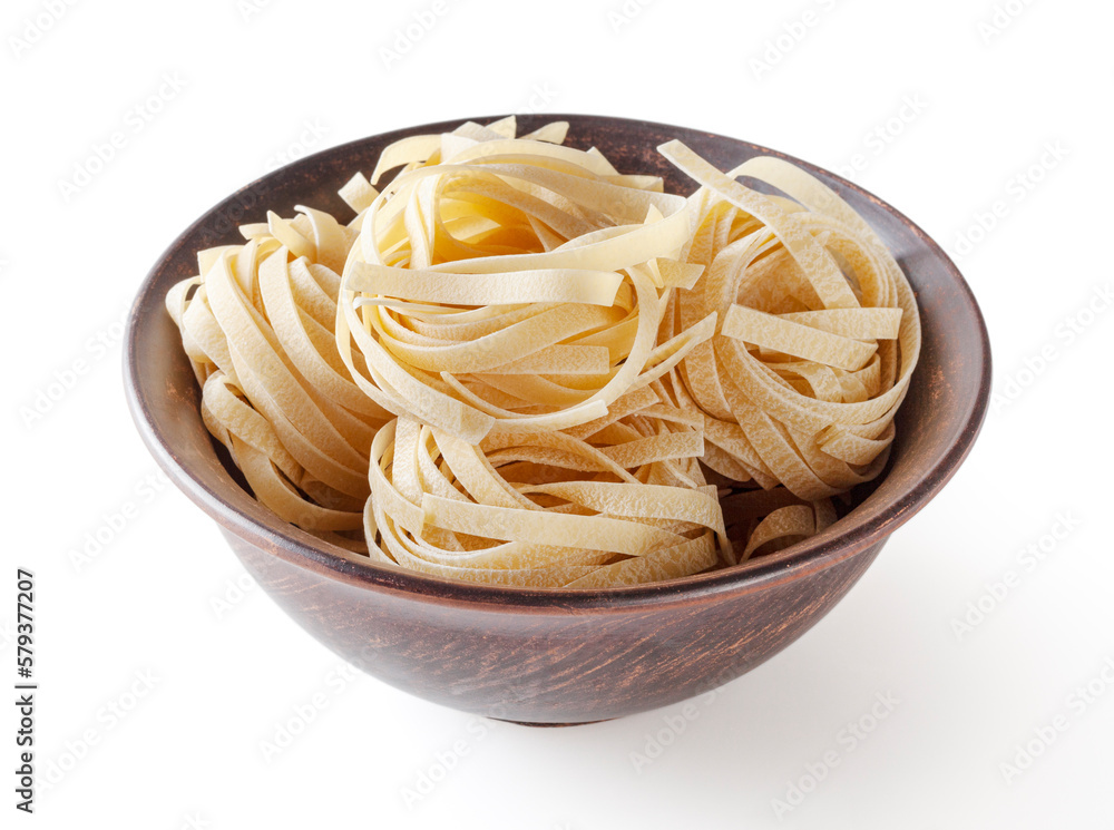 Uncooked tagliatelle pasta in ceramic bowl isolated on white background with clipping path