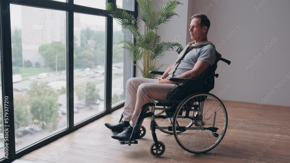 Senior man sitting in wheelchair near window at home Senior man sitting in wheelchair near window at home