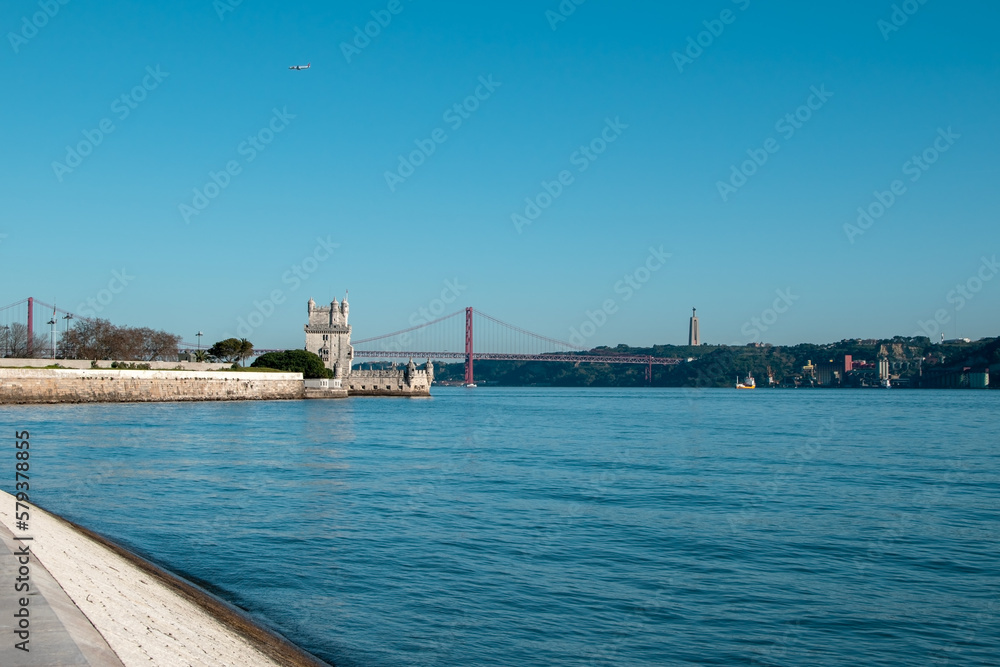 View of Tower of Belem and Ponte 25 de Abril Bridge at sunset, Lisbon, Portugal on the Tagus River