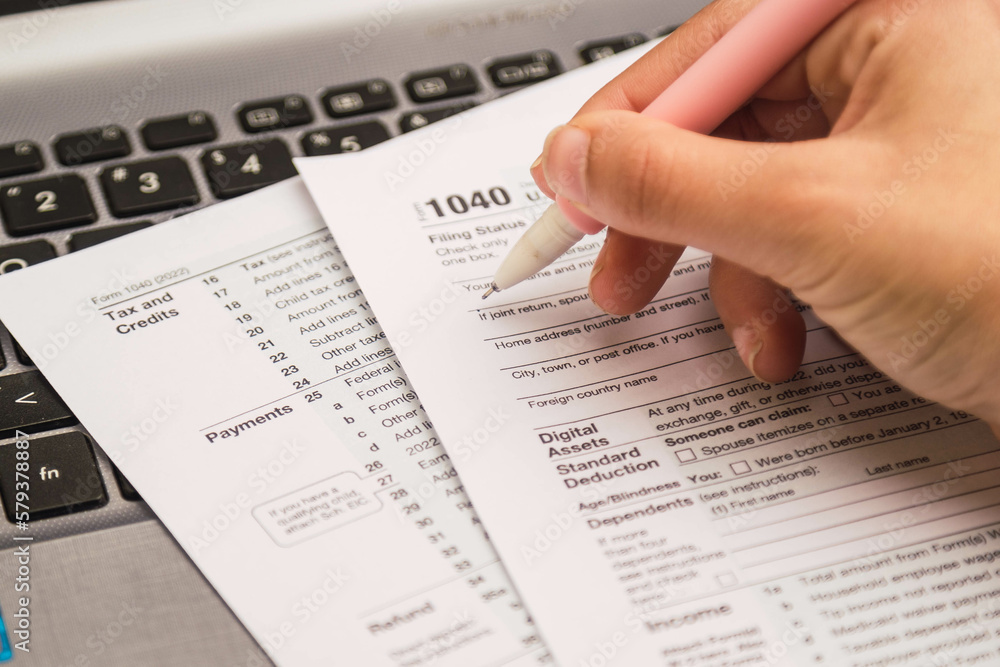 Fototapeta premium woman hand filling 1040 tax forms , United States tax form, a laptop on a desk. US individual income tax return. Accountant working with US tax forms