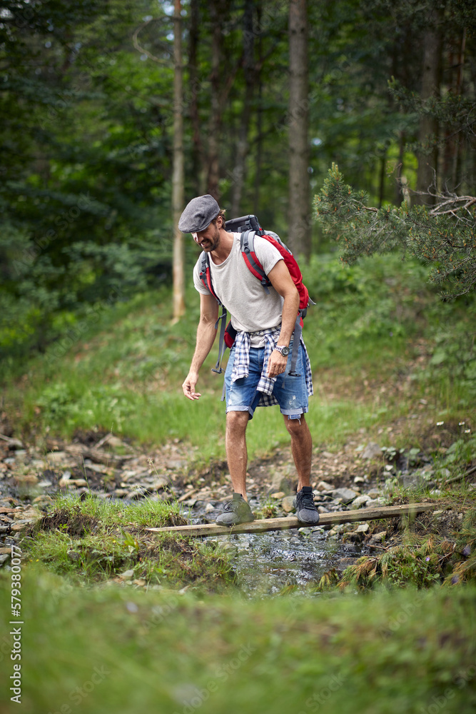 Young man Crossing River.Journey in the forest. Healthy lifestyle
