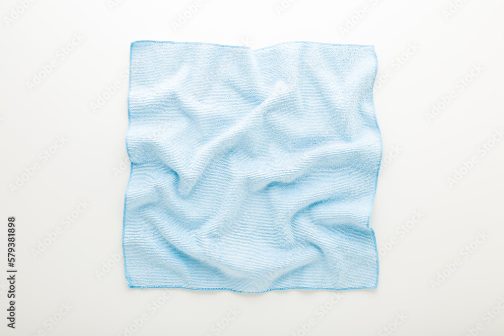 Light blue wrinkled dry soft microfiber rag for different surfaces wiping on white table background. Top down view. Closeup. Light blue wrinkled dry soft microfiber rag for different surfaces wiping on white table background. Top down view. Closeup.