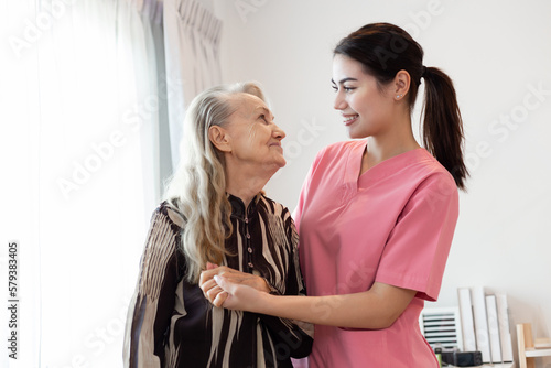 Young professional confident skilled woman doctor visiting old patient lady at home for treatment control care giving. Nurse talking to Caucasian senior patient. Healthcare concept
