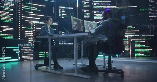 Diverse Young Man and Woman Working on Desktop Computers, Surrounded by Big Screens Displaying Code Lines. Professional Computer Engineers Developping Autonomous Algorithm for Generative AI photo