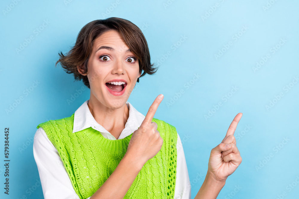 Photo of positive impressed cute woman with bob hairstyle dressed green waistcoat directing empty space isolated on blue color background Photo of positive impressed cute woman with bob hairstyle dressed green waistcoat directing empty space isolated on blue color background