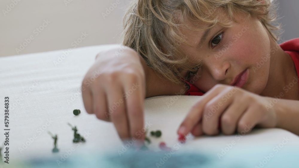 Small boy plays with miniature figurines at home. Child playing with toy soldiers close up face Small boy plays with miniature figurines at home. Child playing with toy soldiers close up face