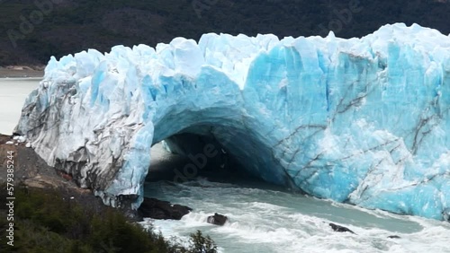 Spectacular view of Perito Moreno Glacier as massive ice blocks break away from the glacier wall and crash into Lake Argentino. Capturing the power of ice calving in Argentine Patagonia.