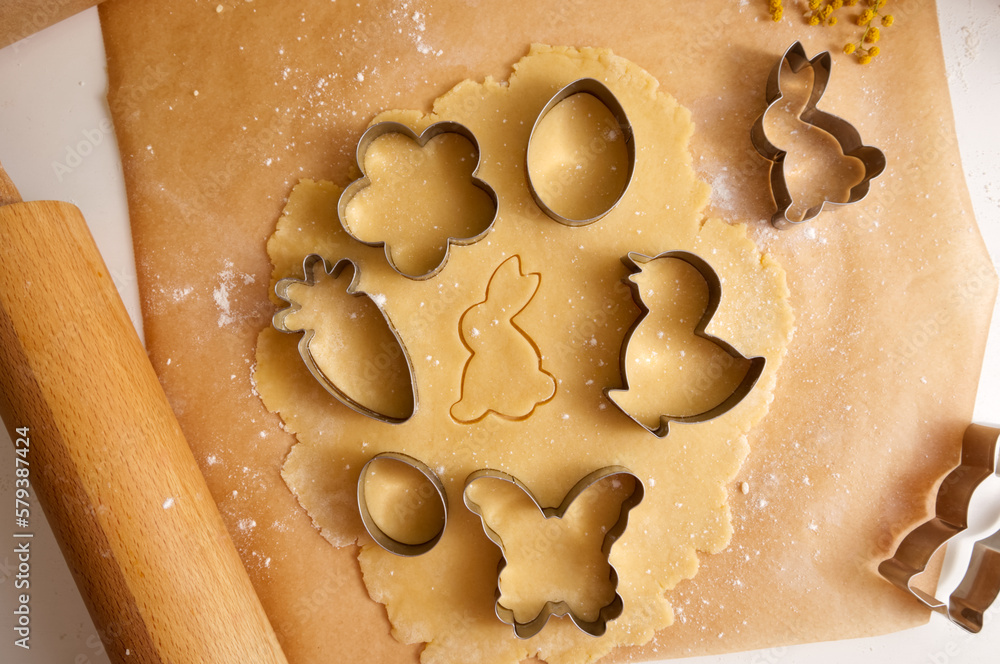 Easter cookie dough and cookie cutters on baking paper close-up Easter cookie dough and cookie cutters on baking paper close-up