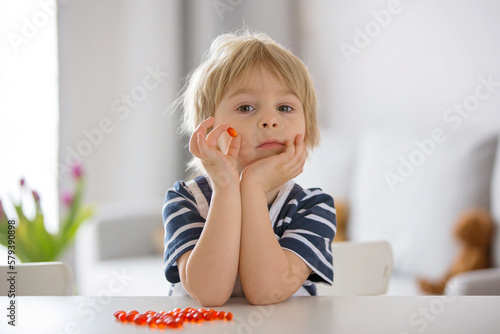 Obraz na plátne Cute little child, toddler boy, eating alfa omega 3 child supplement vitamin pil