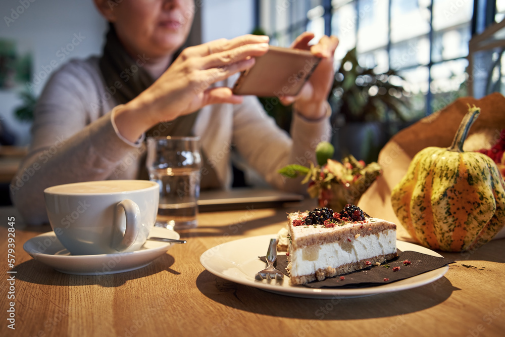 Sweet cake in a coffee bar with a woman photographing with her smartphone Sweet cake in a coffee bar with a woman photographing with her smartphone