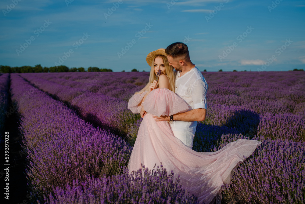 Fototapeta premium a woman in a pink dress and hat and a man in a white shirt are walking in a lavender field..