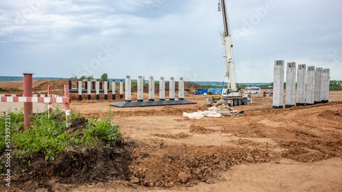 Cleaning of bulky garbage by a machine crane on a construction site. Construction of a new road bridge. Reinforced concrete columns or supports for the installation of a highway.