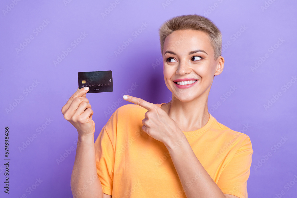 Portrait of charming cheerful girl toothy smile look direct finger arm hold debit card isolated on purple color background Portrait of charming cheerful girl toothy smile look direct finger arm hold debit card isolated on purple color background