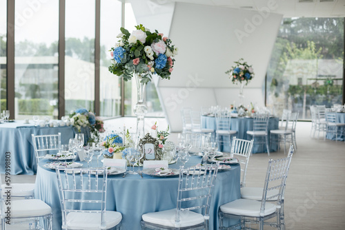 Served wedding table with decorative fresh pink, blue flowers and candles. Celebration details. Wedding decoration and decor, floristic concept