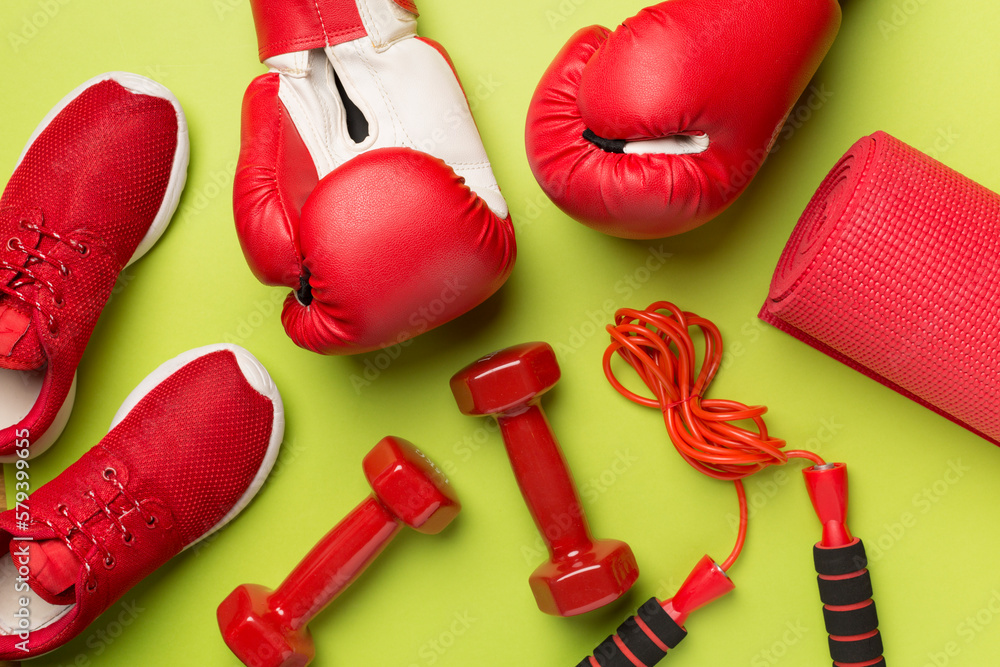 Red sport equipment on color background, top view