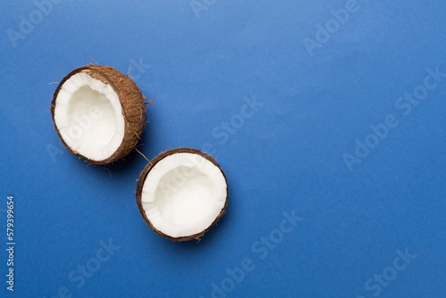 Coconut with leaves on color background, top view