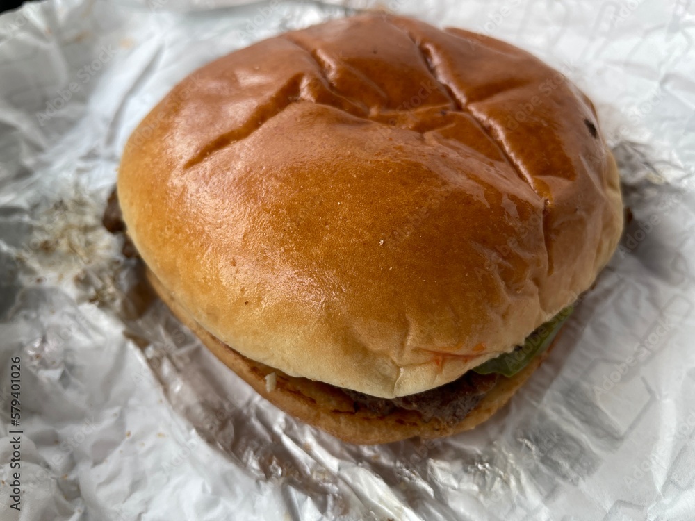 A homemade hamburger laying on a foil wrap A homemade hamburger laying on a foil wrap