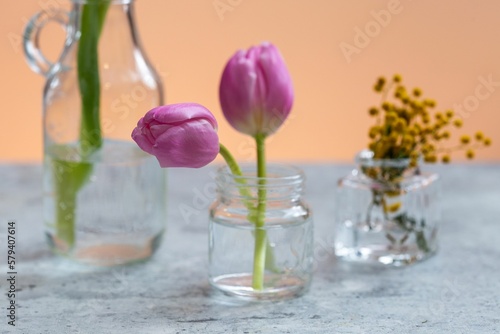 Three transparent glass vases on a table with various flowers