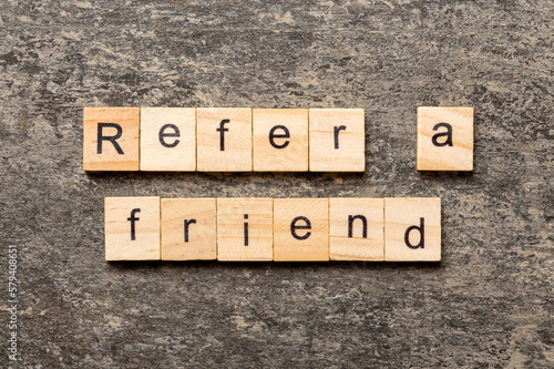 refer a friend word written on wood block. refer a friend text on table, concept