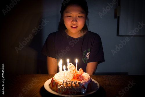 Young asian girl blowing out candles on her birthday cake