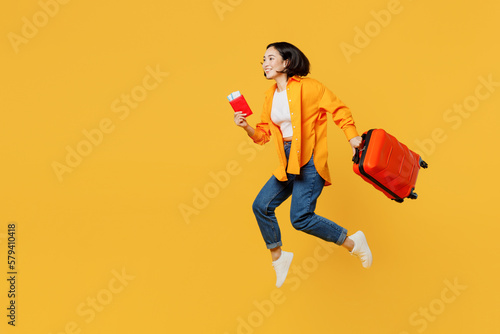 Fotografia Young woman wear summer casual clothes hold passport ticket bag jump high isolated on plain yellow background