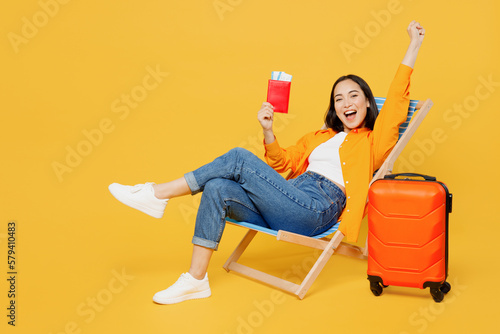 Fotobehang Young winner woman in summer clothes sit in deckchair hold passport ticket isolated on plain yellow background