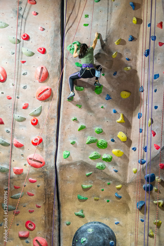 Young girl climbing up indoor rock climbing