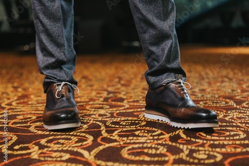 Stylish man in textured gray suit pants and brown and black brogue shoes